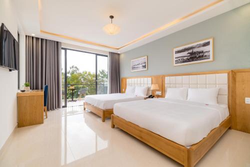 a hotel room with two beds and a balcony at Babylon Hoi An Central Villa in Hoi An