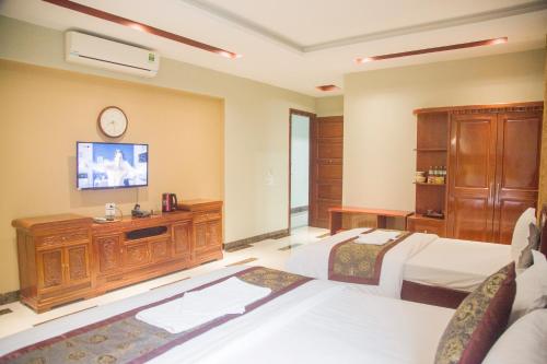 a bedroom with two beds and a tv on the wall at Khách Sạn Hoàng Gia Lào Cai - Hoang Gia Hotel in Lao Cai