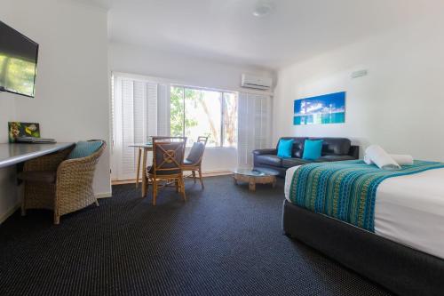 a hotel room with a bed and a desk and a couch at Sonia's At Ramada Resort Free Wifi in Port Douglas