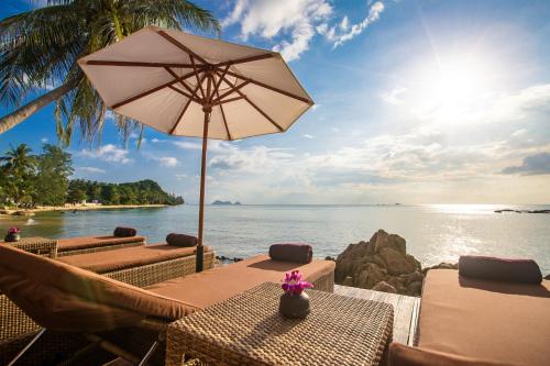 a table with an umbrella next to the water at Beyond The Blue Horizon Boutique Bungalows in Haad Chao Phao