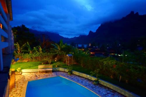 a swimming pool at night with mountains in the background at Villa Vaiana EURL Vaiana Faratea in Paopao