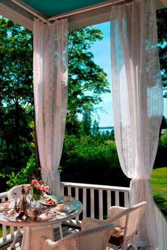 a table and chairs on a porch with curtains at Hotel Töyrylä Manor in Artjärvi