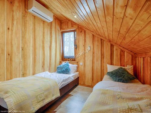 two beds in a room with a wooden ceiling at Domek Fiona in Boszkowo
