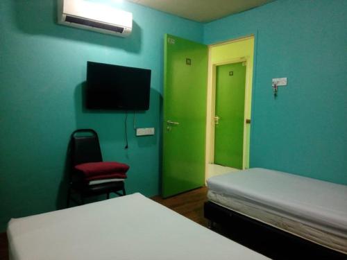 a bedroom with green walls and a bed and a chair at Petaling Street Hotel Chinatown in Kuala Lumpur
