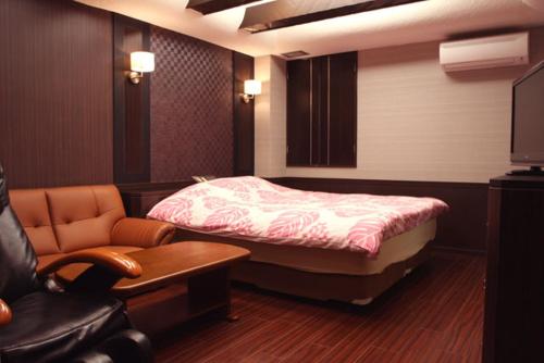 a bedroom with a bed and a chair and a couch at Hotel GOLF Atsugi (Adult Only) in Atsugi