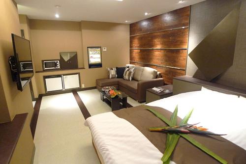 a hotel room with a bed and a couch at Hotel GOLF Nirasaki (Adult Only) in Nirasaki