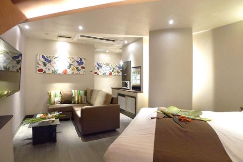 een hotelkamer met een bed en een bank bij Hotel GOLF Nirasaki (Adult Only) in Nirasaki