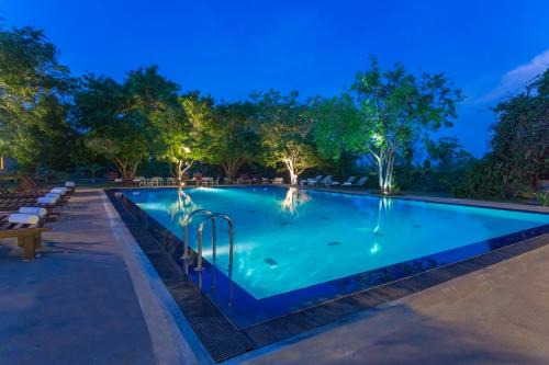 a swimming pool at night with trees in the background at Kassapa Lions Rock in Sigiriya