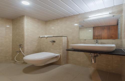 a bathroom with a toilet and a sink and a mirror at Hotel Karuna Residency in Mangalore