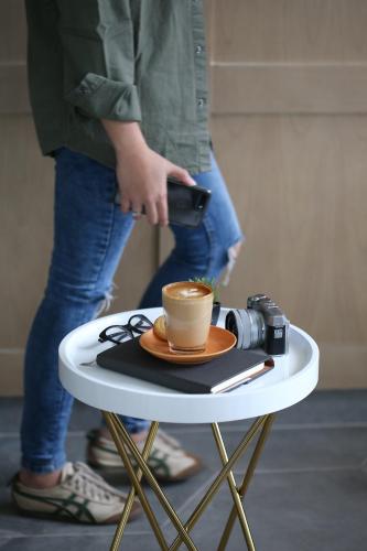 a person standing on a table with a cup of coffee at Kampi Hotel Tunjungan - Surabaya in Surabaya
