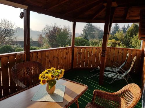 a porch with a table and chairs and a vase of flowers at Kaktusz Villa Heviz in Hévíz