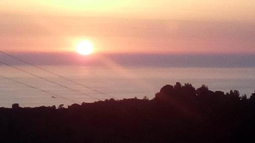 a sunset with the sun rising over the trees at Monika Lefkada in Tsoukaladhes