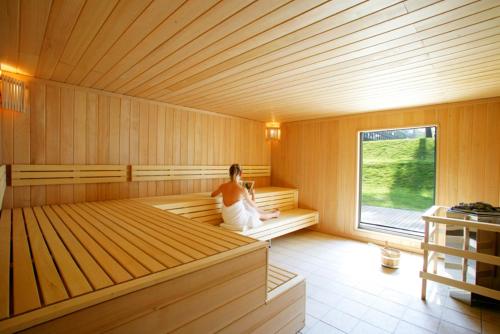 a woman is sitting in a sauna at Hotel Dolce La Hulpe Brussels in La Hulpe