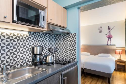 a kitchen with a sink and a bed in a room at Aparthotel Adagio Paris Montmartre in Paris