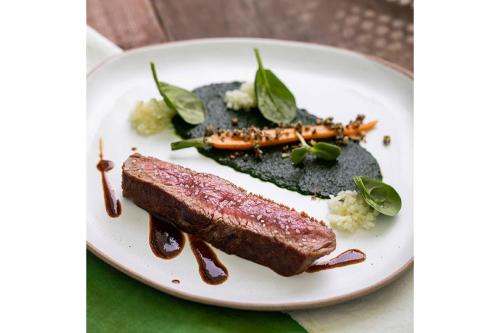 a plate of food with meat and vegetables on a table at Cape Fahn Hotel - Private Islands Samui in Choeng Mon Beach