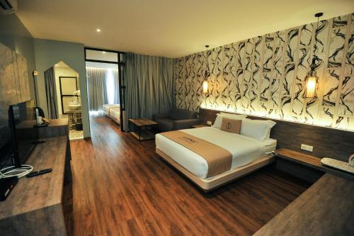 a hotel room with a bed and a television at Iconic Suites & Pods Hotel in Ipoh