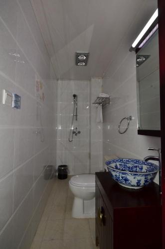 a bathroom with a toilet and a sink with a bowl at Qianmen Courtyard Hotel in Beijing
