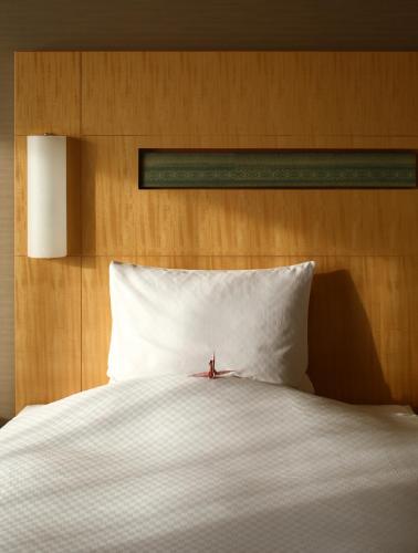 a large white bed with a wooden head board at Hotel Okura Fukuoka in Fukuoka