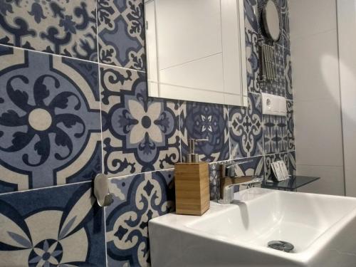 Łazienka wyposażona jest w umywalkę oraz niebiesko-białe kafelki. w obiekcie Apartamentos El Vestuario w Kadyksie