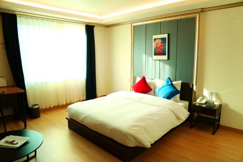 a bedroom with a large white bed with colorful pillows at Lavita hotel in Seoul