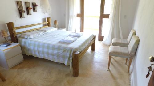 a bedroom with a bed and a chair and a window at Casa do Capão in Vale do Capao