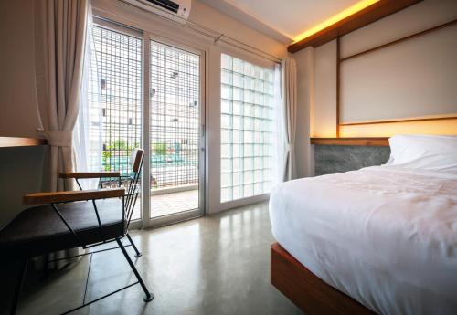 ナコーンシータンマラートにあるLaekhon Nonbaiのベッドルーム1室(ベッド1台、椅子、窓付)