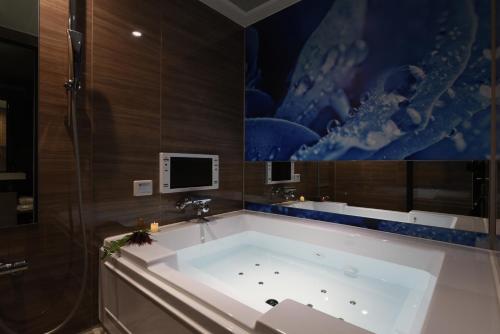 La salle de bains est pourvue d'une grande baignoire et d'une télévision. dans l'établissement Hotel ZEN Sennichimae (Adult Only), à Osaka