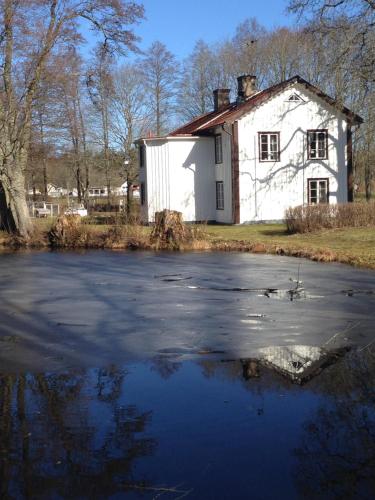 an old white house with a pond in front of it at KvarnDammens Bed & Breakfast in Vetlanda
