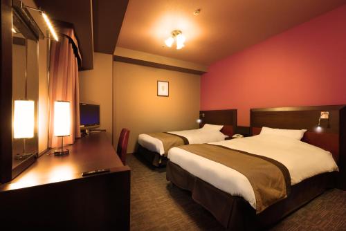 a hotel room with two beds and a television at Hotel Monte Hermana Sendai in Sendai