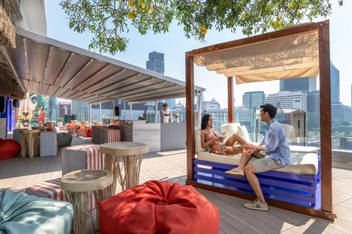 a man and woman sitting on a bench in front of a beach at Novotel Bangkok Platinum Pratunam - SHA Plus Certified in Bangkok