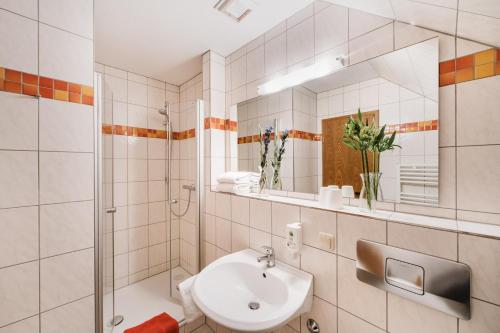 a white bathroom with a sink and a mirror at Hotel Achtermann in Braunlage