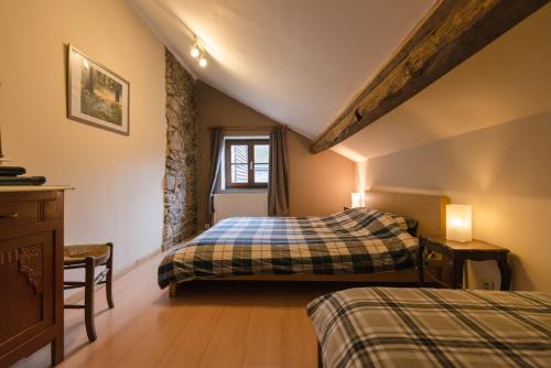 1 dormitorio en el ático con 2 camas y ventana en B&B Les Trois Voisins, en Bourseigne-Vieille