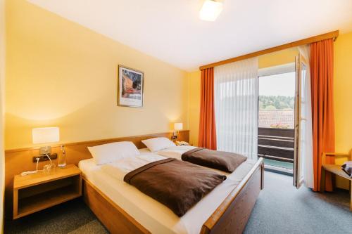 a bedroom with a large bed and a large window at Hotel Achtermann in Braunlage