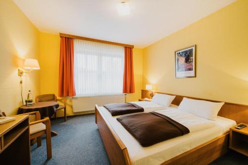 a hotel room with a bed and a desk at Hotel Achtermann in Braunlage