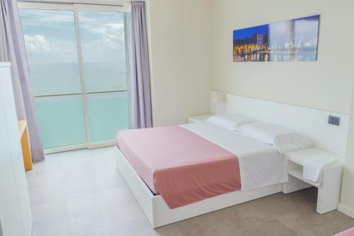 a white bedroom with a bed and a large window at Garda Rooms in Desenzano del Garda