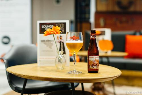 a bottle of beer and a glass of wine on a table at ibis De Panne in De Panne