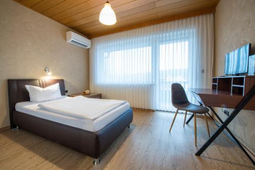 a bedroom with a bed and a desk and a computer at Hotel Es Lämmche in Breuberg