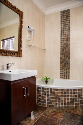 a bathroom with a tub and a sink and a mirror at Schroderhuis Guesthouse NO LOADSHEDDING GOOD WIFI in Upington