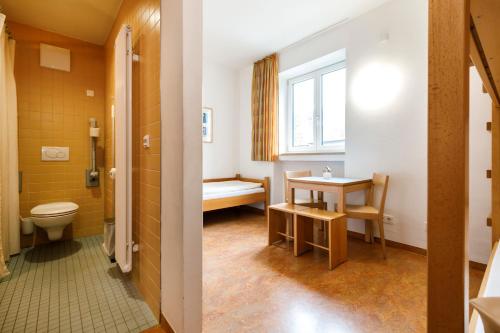 a bathroom with a toilet and a table and a window at Jugendherberge Garmisch-Partenkirchen - membership required! in Garmisch-Partenkirchen
