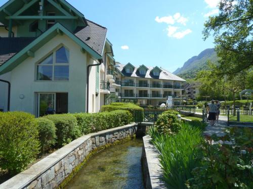 a house with a stream in front of a building at La Baie des Voiles 2 chambres 4 à 6 personnes au bord du lac plage privée in Duingt