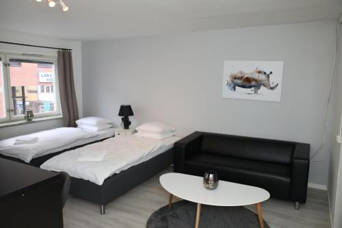Pokój z 2 łóżkami, kanapą i stołem w obiekcie Fastliving Apartment Hotel w mieście Västerås
