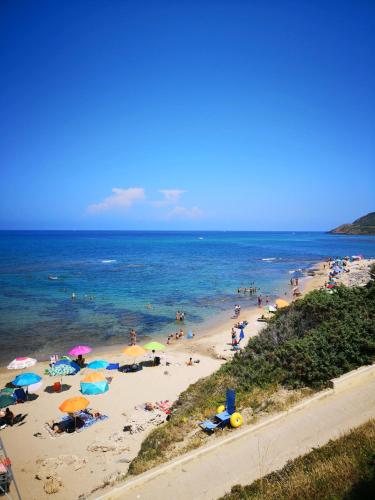 a beach with a bunch of people and umbrellas at Su Cuile historical country house with barbecue in Martis