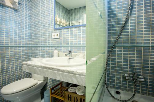 Un baño con azulejos azules, lavabo e inodoro. en Silencio, en Sierra Nevada