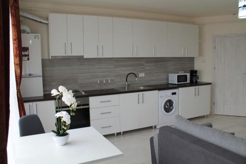 a kitchen with white cabinets and a table with flowers at VISAJ Residence in Timişoara