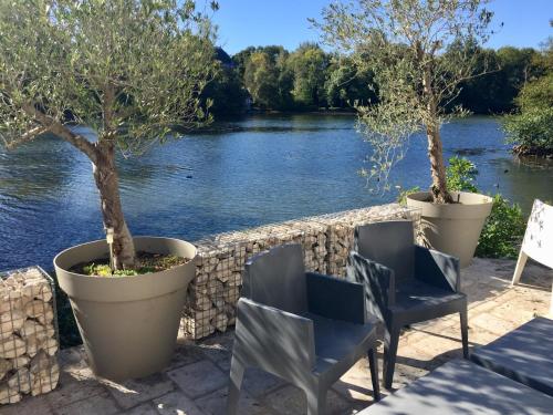 two chairs and trees sitting next to a river at Maison d'Hôtes Moulin Saint Julien in Olivet