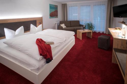 a bedroom with a large white bed with a red carpet at Hotel Garni Schmieder’s Ochsen in Seelbach