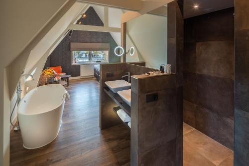 a bathroom with a large tub and a sink at Het Polderhuis in Den Burg