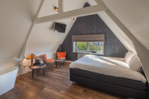 a attic bedroom with a bed and a window at Het Polderhuis in Den Burg