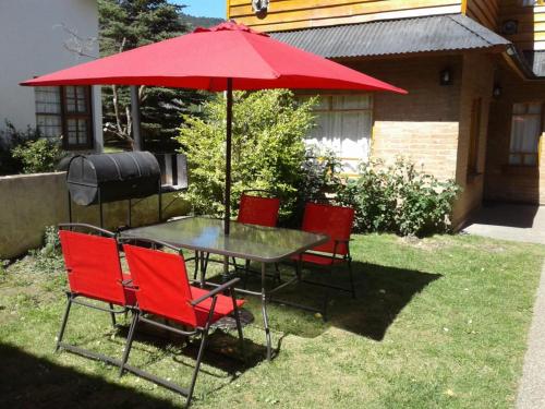 a table with four chairs and a red umbrella at Cabañas Del Lacar in San Martín de los Andes
