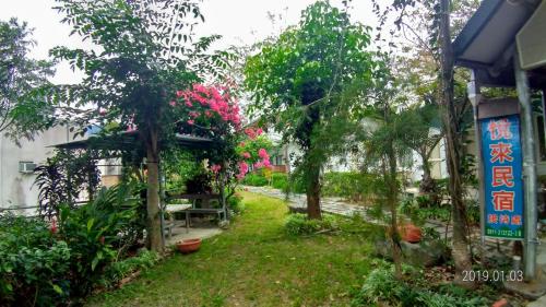 a garden with pink flowers and trees next to a building at 悦來民宿 台東縣民宿334號 in Taiping
